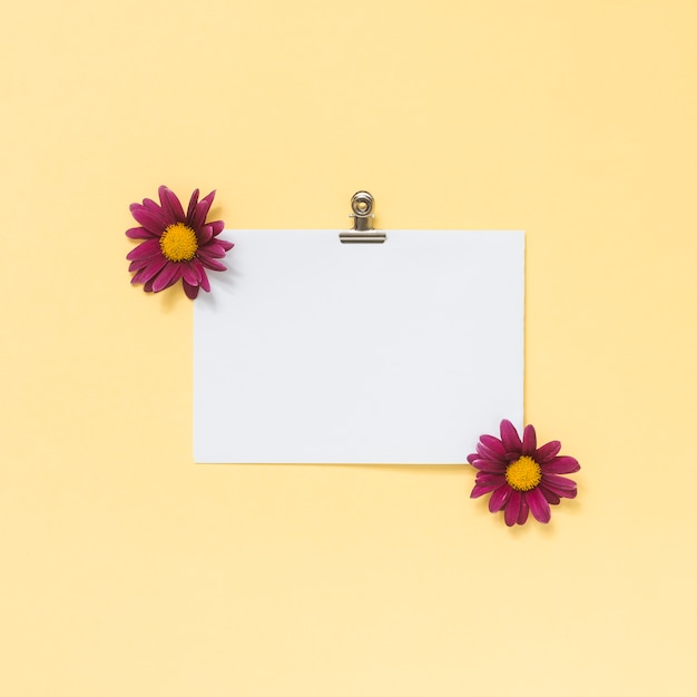 Foto grátis folha de papel em branco com pequenas flores na mesa