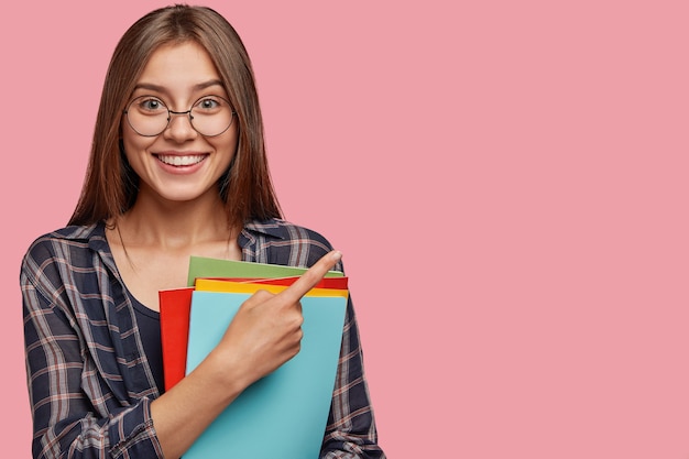 Foto de estúdio de uma bela jovem empresária posando contra a parede rosa com óculos