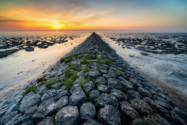 Foto incrível de uma praia rochosa à distância do pôr do sol