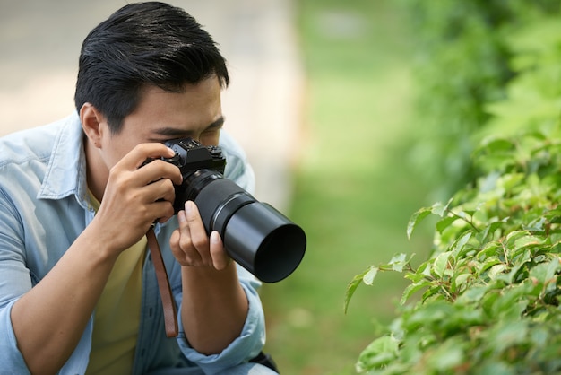 Fotógrafo asiático tirando fotos macro de folhas verdes