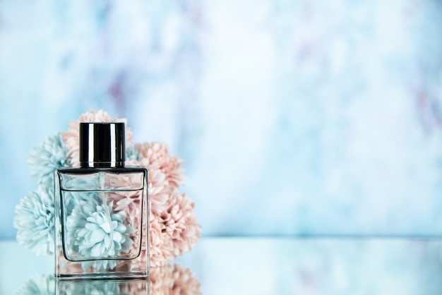 Foto grátis frasco de perfume com flores de frente no espaço livre de fundo azul claro