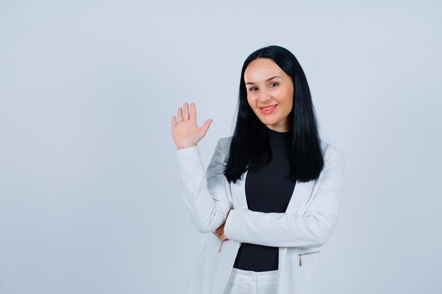 Foto grátis garota sorridente está mostrando oi, levantando a mão no fundo branco