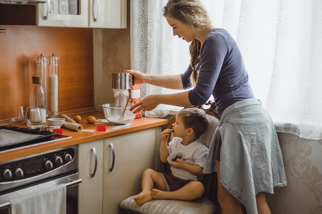 garotinho na cozinha ajuda a mãe a cozinhar. a criança está envolvida na culinária.