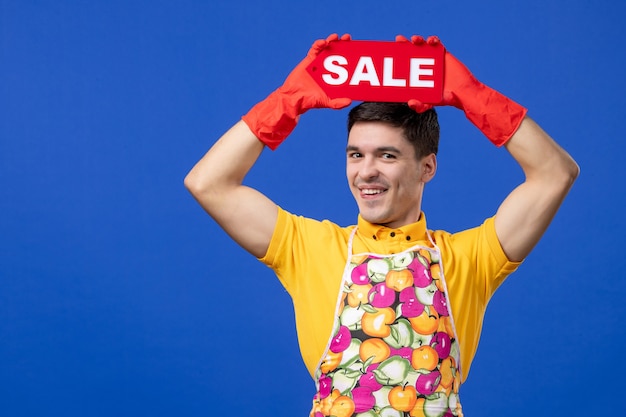 Foto grátis governanta engraçada masculina de vista frontal em uma camiseta amarela, levantando o sinal de venda sobre a cabeça dele no espaço azul