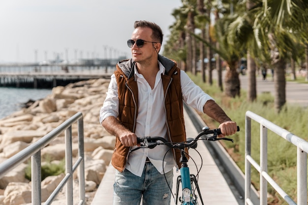 Foto grátis homem caminhando ao lado de sua bicicleta ao ar livre