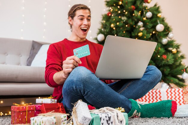 Homem chocado com cartão de crédito e laptop