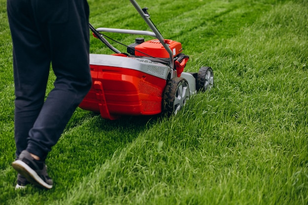 Homem cortando grama com motor de gramado no quintal