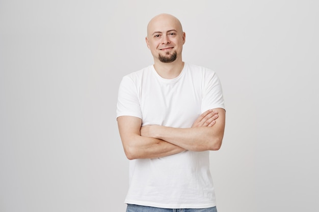 Foto grátis homem de barba careca sorridente e confiante cruzando os braços sobre o peito