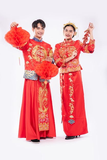 Foto grátis homem e mulher vestindo terno cheongsam celebram o ano novo chinês com lâmpada vermelha e fogos de artifício