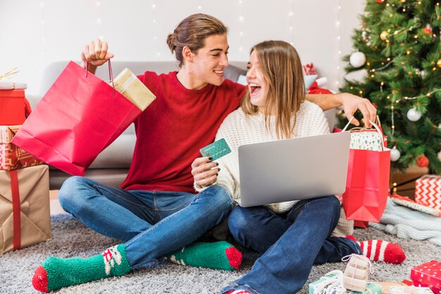 Homem excitado e mulher com compras e laptop