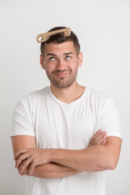 Foto grátis homem jovem, olhar, pente, que, é, aderido, em, seu, cabelo, ficar, contra, fundo branco