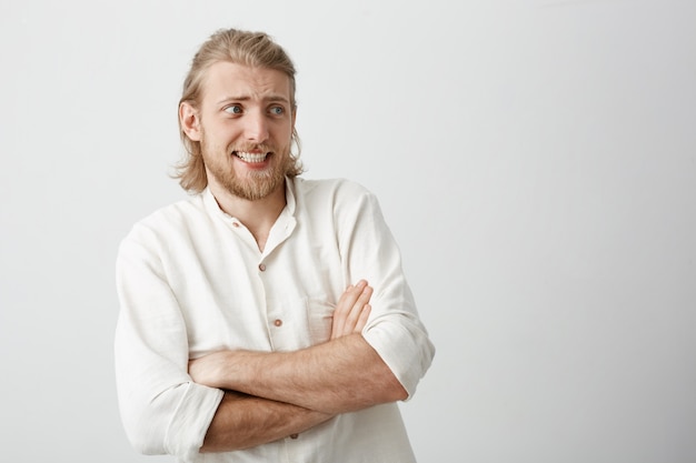 Foto grátis homem loiro encantador com corte de cabelo elegante em pé com as mãos cruzadas