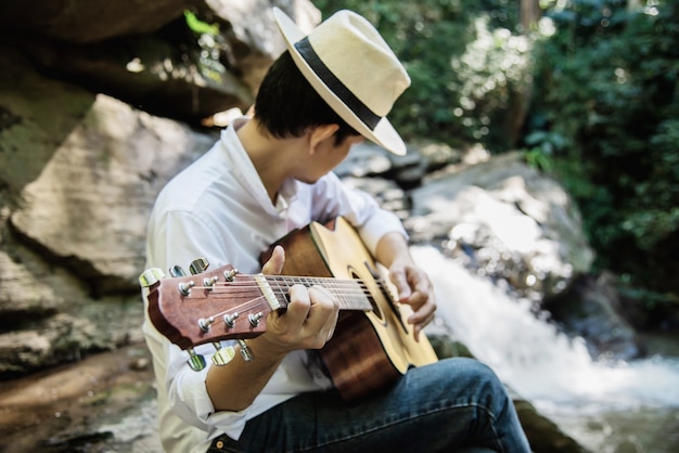 Foto grátis homem toca guitarra perto da cachoeira