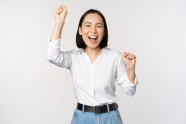 Foto grátis imagem de feliz mulher asiática sortuda hooray gesto ganhando e comemorando triunfante levantando hads e rindo em pé sobre fundo branco