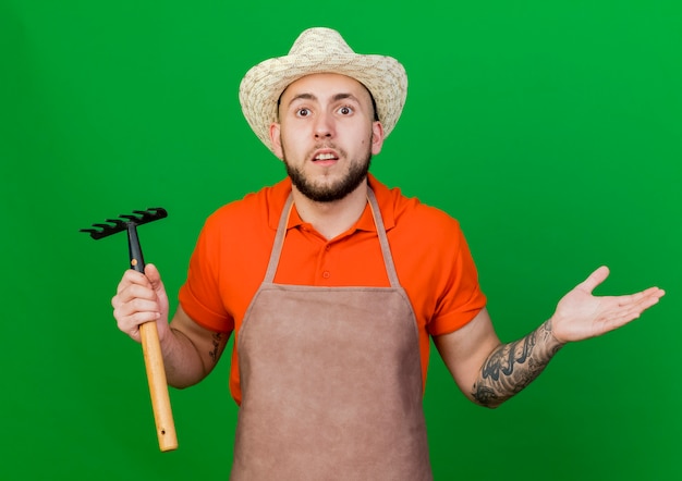 Foto grátis jardineiro chocado com chapéu de jardinagem segurando o ancinho