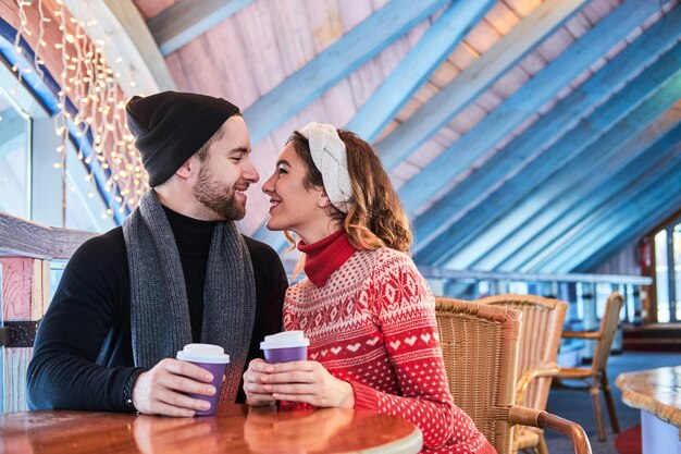 Jovem casal atraente em um encontro no café, conversando e beijando na época do Natal