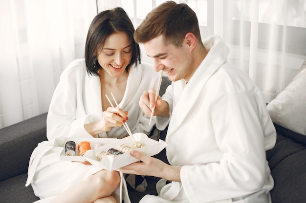 Foto grátis jovem casal de roupões de banho comendo sushi.