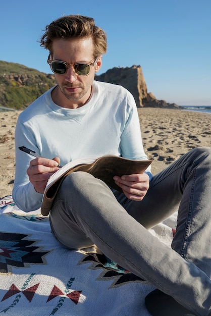 Jovem escrevendo em sua agenda na praia