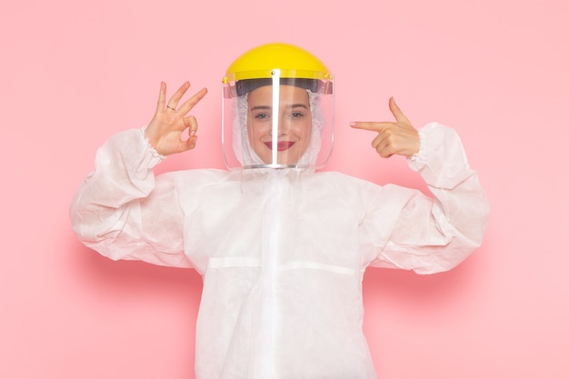 Foto grátis jovem mulher bonita em um terno branco especial e capacete amarelo sorrindo e posando em rosa