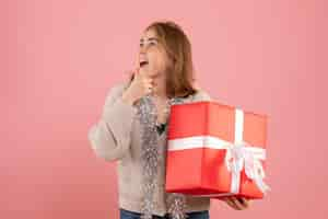 Foto grátis jovem mulher segurando um presente de natal de frente