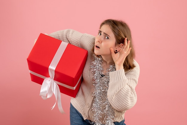 Foto grátis jovem segurando um presente de natal rosa