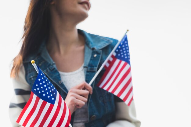 Jovem senhora sorridente segurando bandeiras americanas