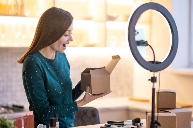 Foto grátis jovem treinador de beleza sorridente apresentando novos produtos de beleza para o público online