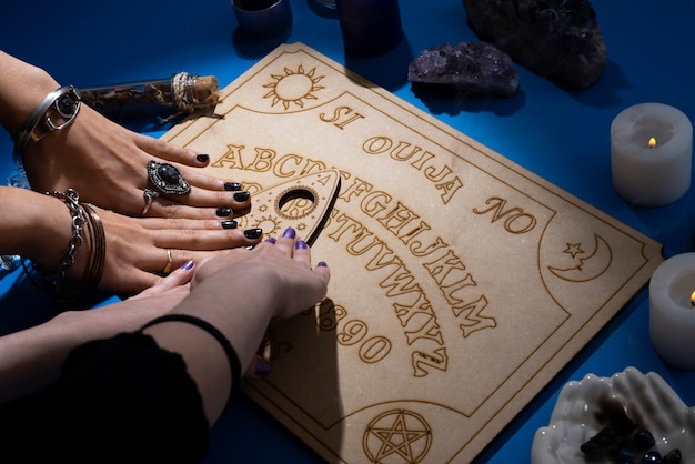 Foto grátis mãos tocando alto ângulo de tabuleiro ouija de madeira