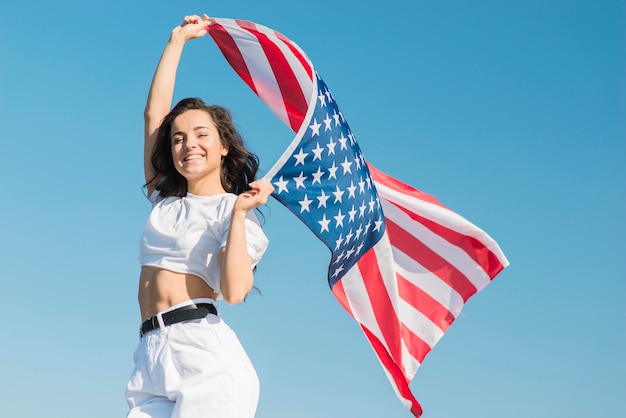 Foto grátis meados de tiro jovem segurando a bandeira dos eua grande e sorrindo