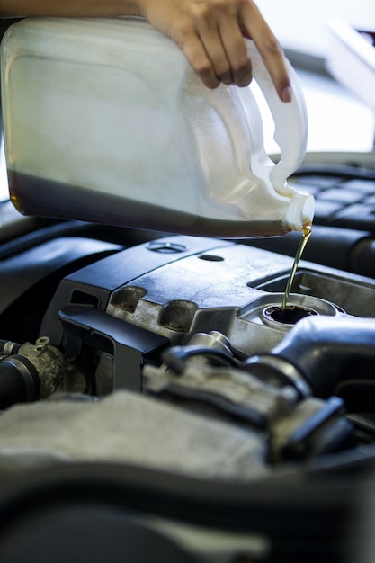 Foto grátis mecânico derramando óleo lubrificante para o motor do carro