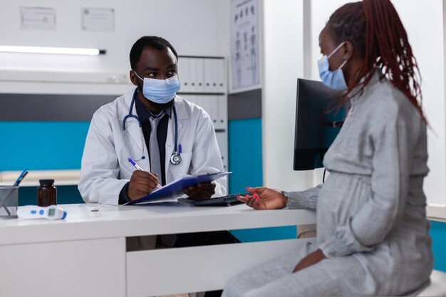 Médico afro-americano e mulher grávida conversando