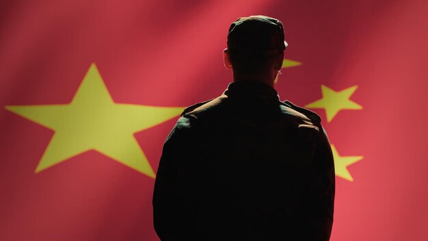 Foto grátis membro do exército chinês fazendo um gesto de mão de saudação para a bandeira da china