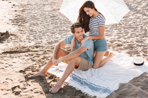 Menina dando massagem ao namorado na praia