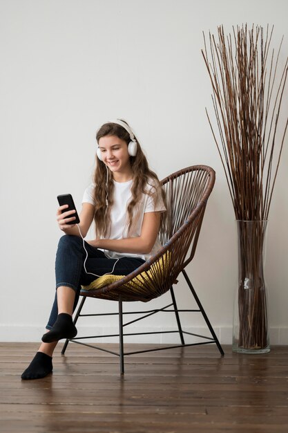 Menina na cadeira ouvindo música em fones de ouvido