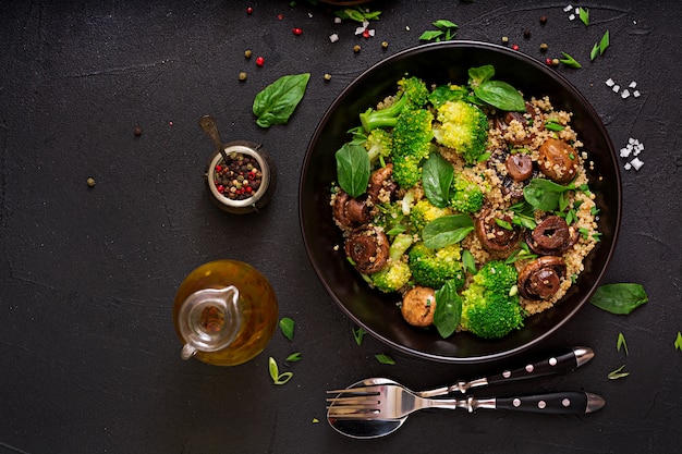 Menu dietético. Salada vegan saudável de legumes - brócolis, cogumelos, espinafre e quinoa em uma tigela. Postura plana. Vista do topo