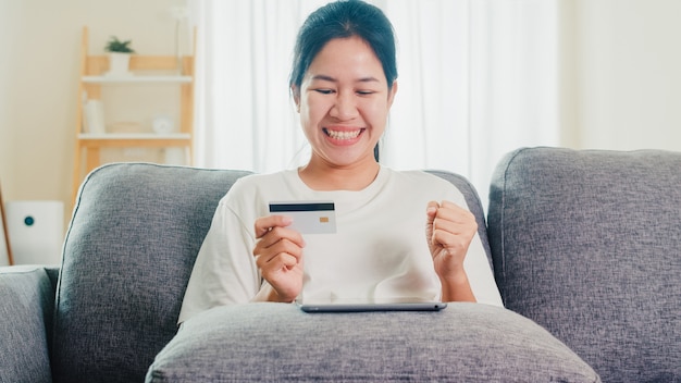 Foto grátis mulher asiática usando tablet, cartão de crédito, compra e compra de comércio eletrônico na internet na sala de estar em casa