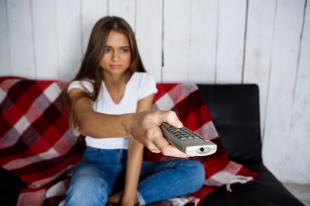 Foto grátis mulher bonita assistindo tv, sorrindo, sentado no sofá em casa.