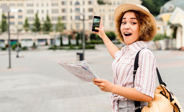 Foto grátis mulher chocada segurando um mapa e um telefone