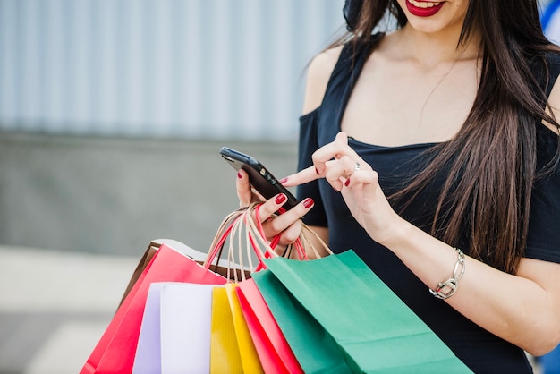 Foto grátis mulher com sacos de compras segurando smartphone