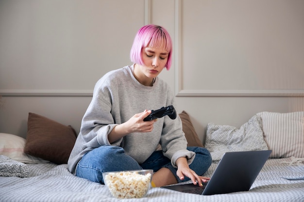 Foto grátis mulher de cabelo rosa brincando com um joystick no laptop