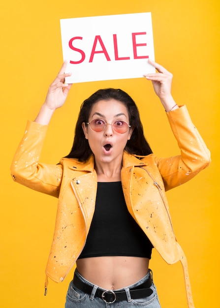 Foto grátis mulher de casaco amarelo segurando um banner de venda