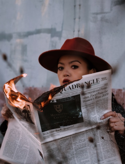 Foto grátis mulher de chapéu marrom segurando jornal em chamas