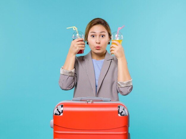 Foto grátis mulher de frente para as férias segurando bebidas frescas no fundo azul claro viagem viagem férias viagem hidroavião