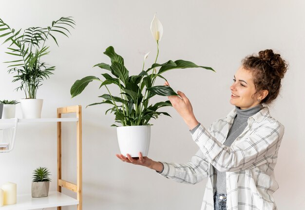 Mulher de tiro médio segurando planta