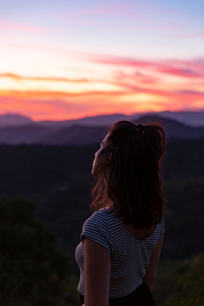 Mulher em pé na frente em um fundo bonito ao amanhecer