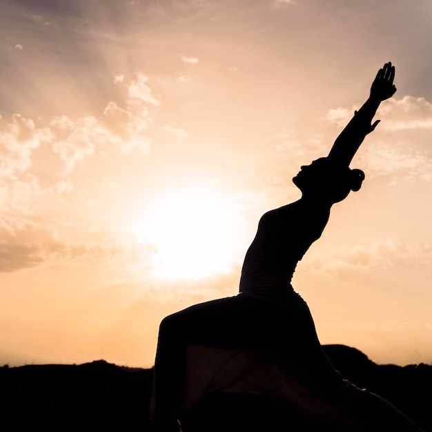 Mulher fazendo yoga com o por do sol