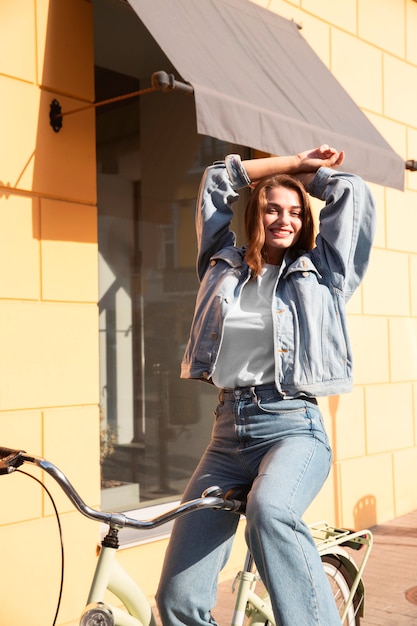 Foto grátis mulher feliz posando em sua bicicleta na rua