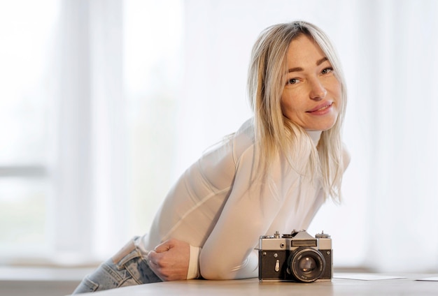 Foto grátis mulher inclinada sobre uma mesa ao lado de uma câmera