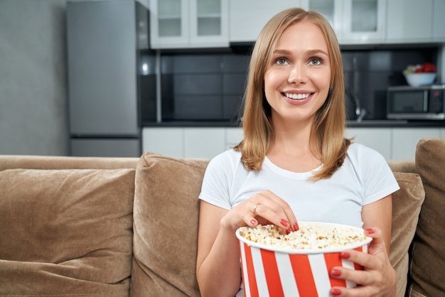 Foto grátis mulher jovem assistindo filme e comendo pipoca em casa