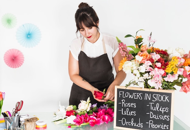 Foto grátis mulher, ordenando, flores, com, ardósia, ligado, escrivaninha vidro